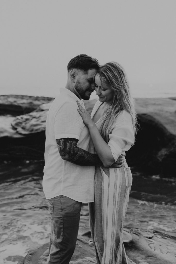 Couple hugging and admiring an engagement ring after their proposal in Ocean Beach, San Diego. Proposing.
