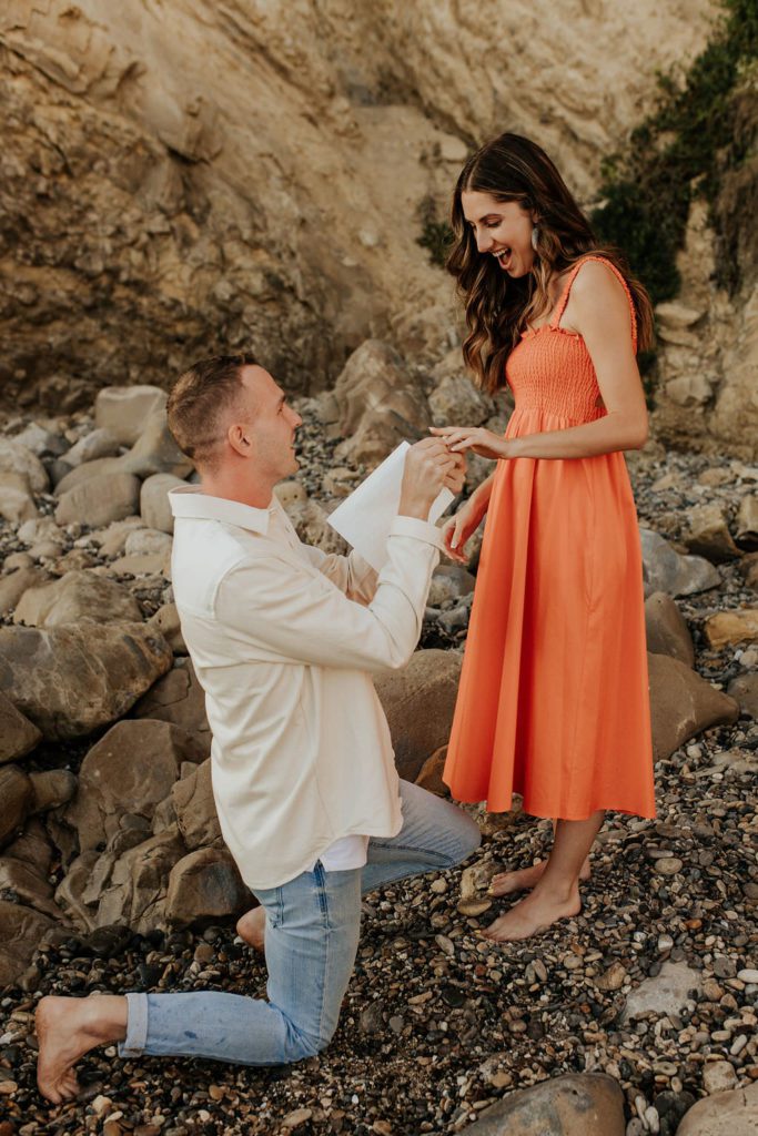 Man proposing to woman and putting a ring on her finger